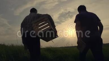 两个商人农民紧紧握手。 他们在田野上谈论美丽的日落，他们用